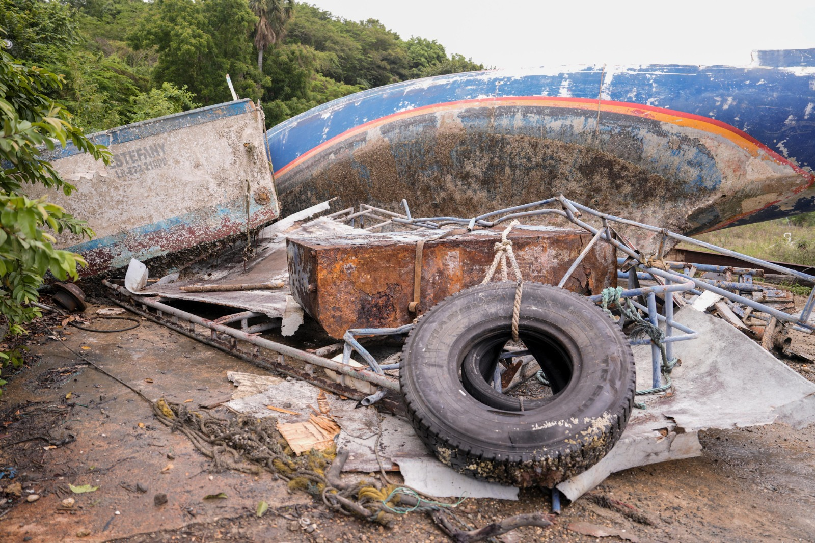 Barco abandonado y escombros en la costa