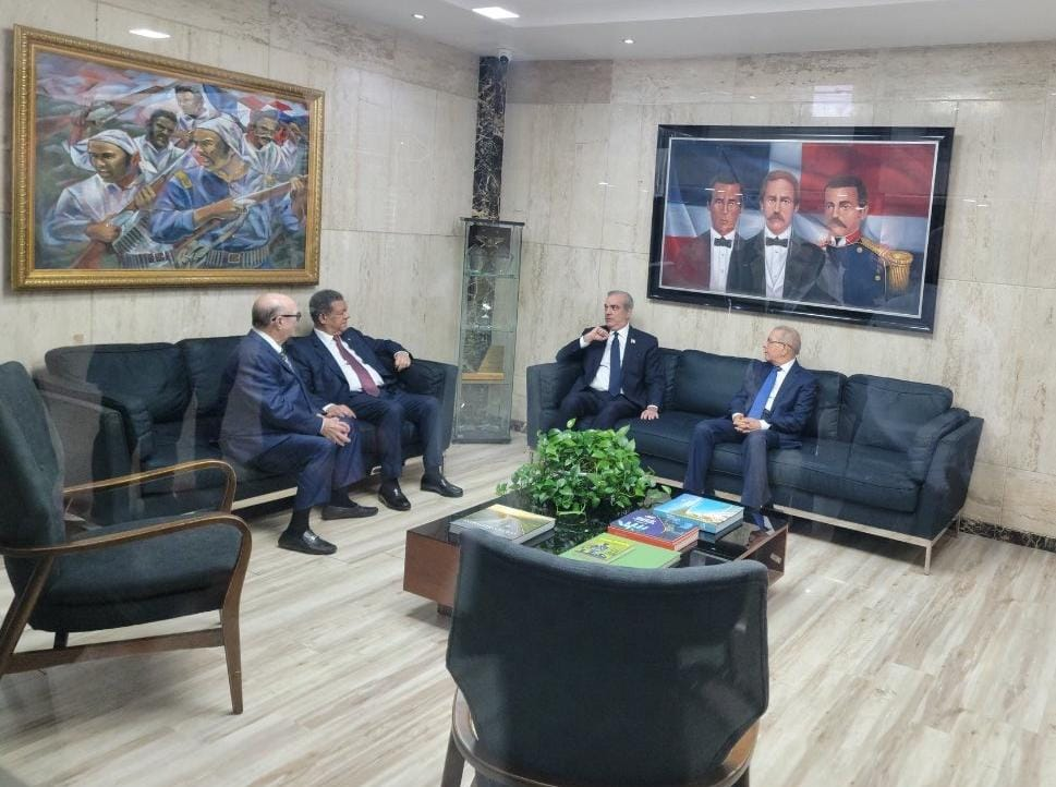 Reunión de hombres en sala con cuadros en la pared.