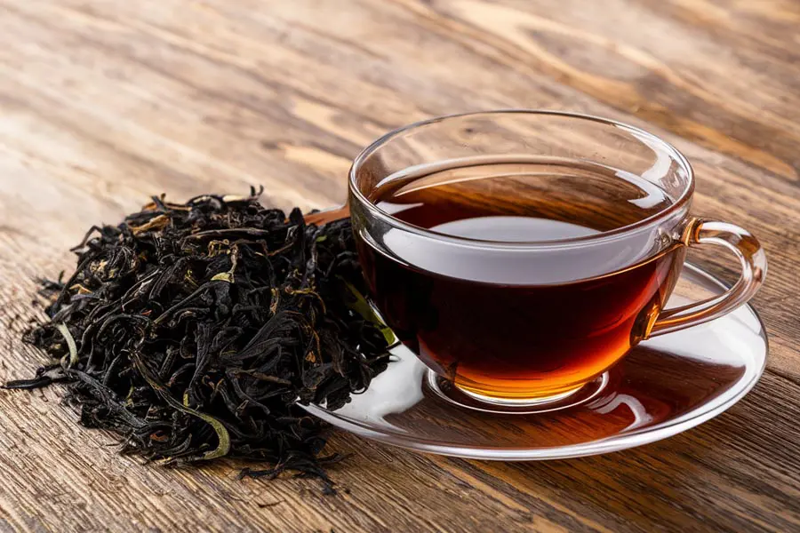 Taza de té negro con hojas secas