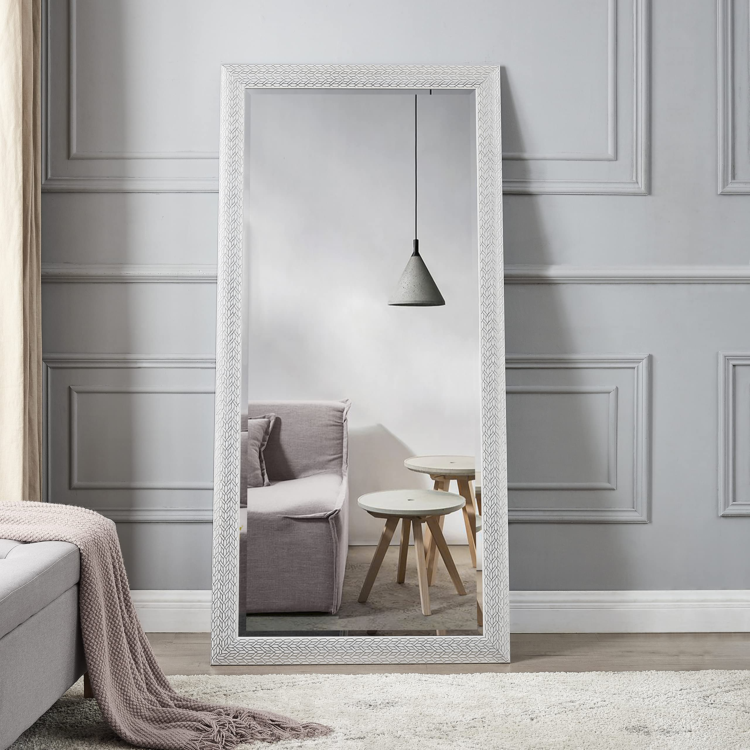 Espejo grande apoyado en pared de salón elegante.