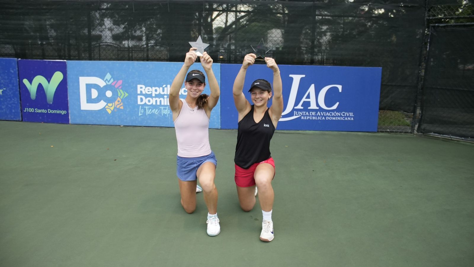 Dos tenistas con trofeos en pista.