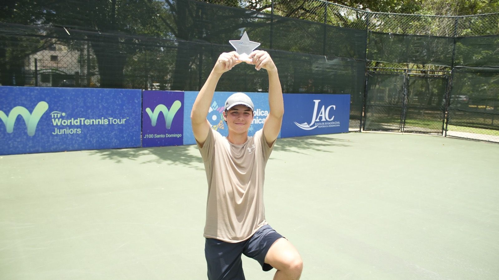 Persona mostrando trofeo en cancha de tenis