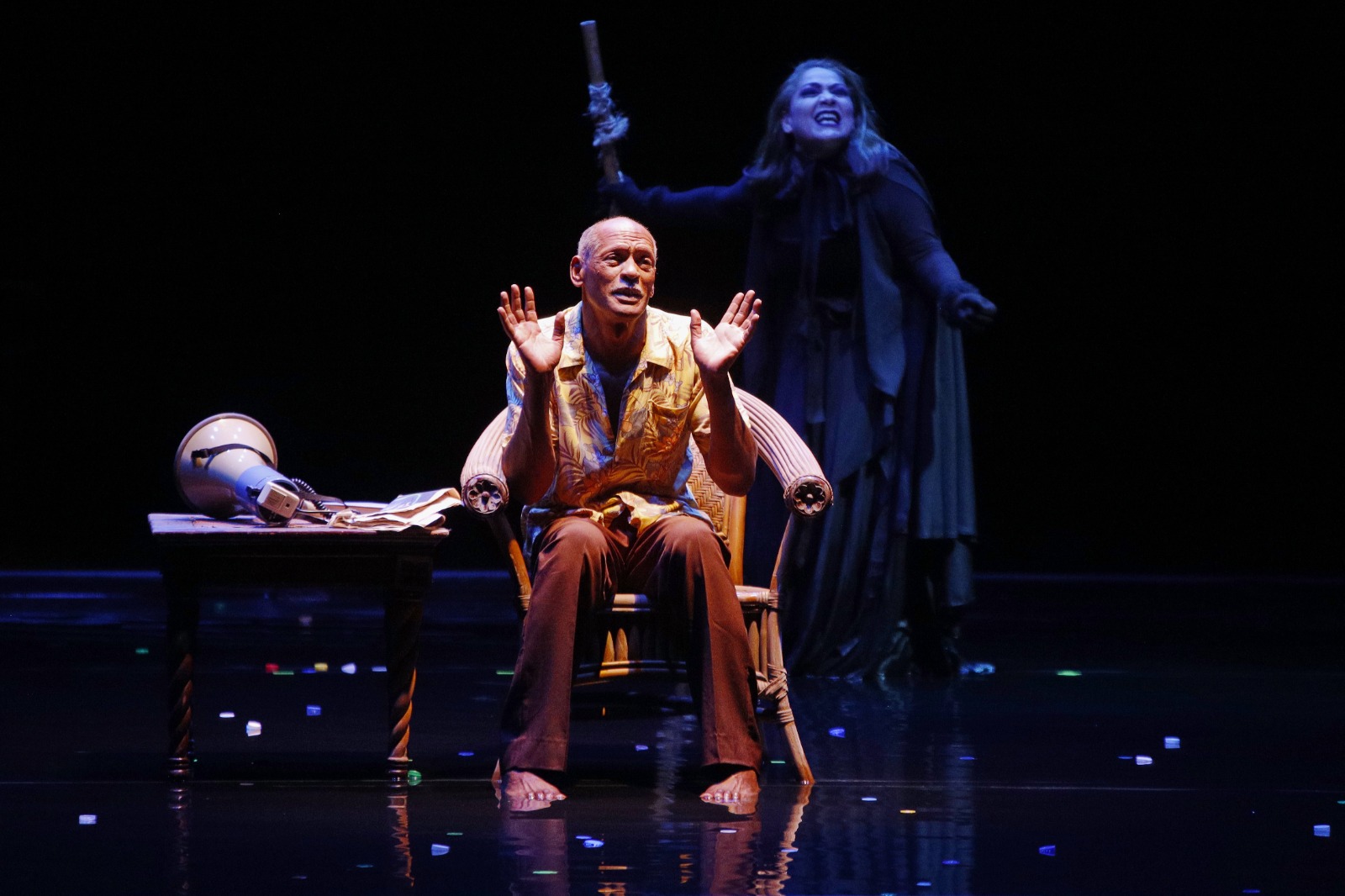 Actores en escena teatral, iluminación dramática.