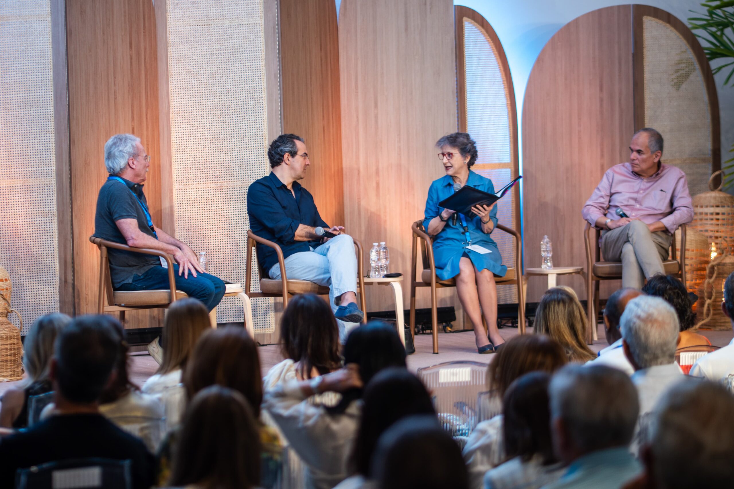 Panel de discusión en evento con cuatro participantes.