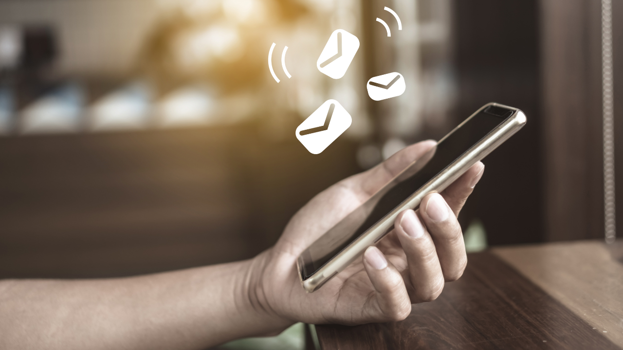 Mano sosteniendo móvil con iconos de mensajes