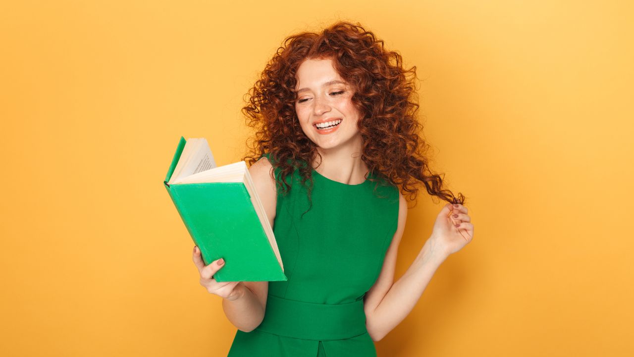 Persona sonriente leyendo un libro verde