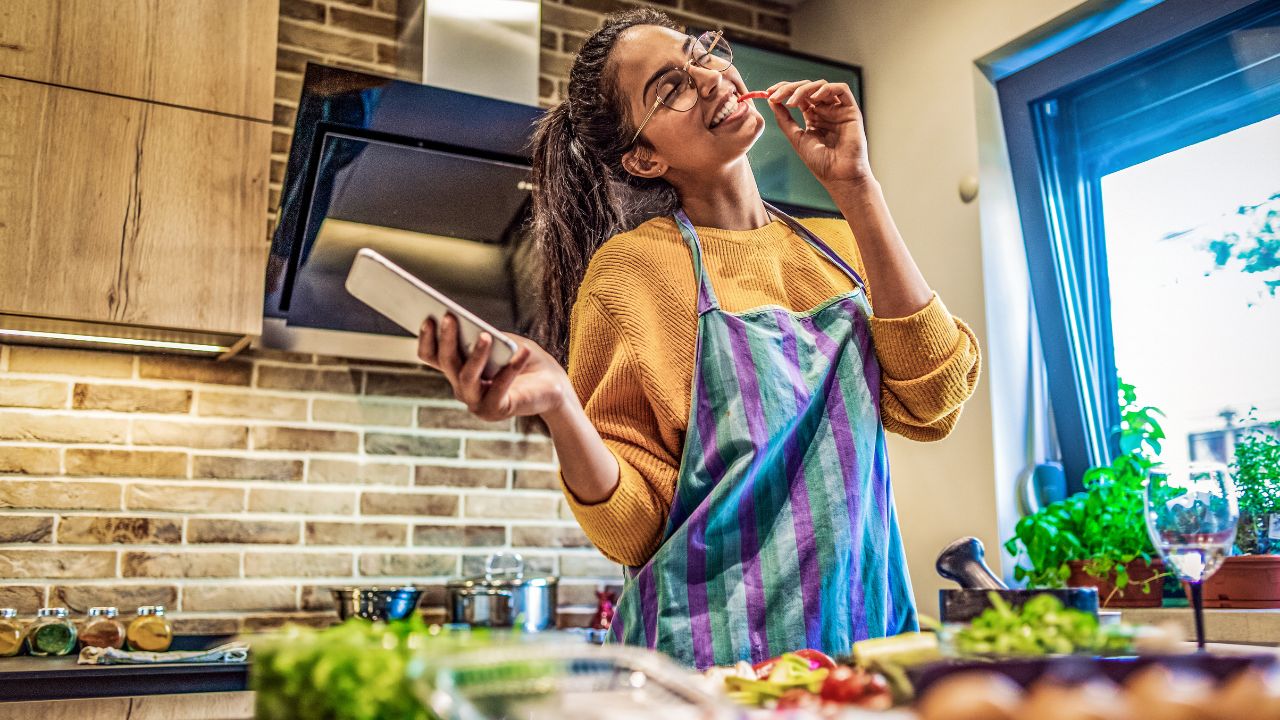 Persona cocinando y mirando una receta en móvil.