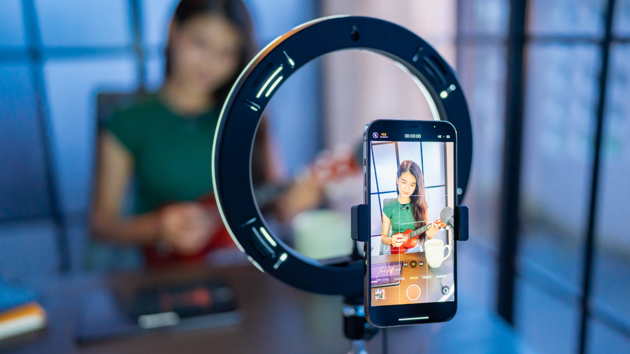 Mujer grabando video tocando ukelele con smartphone.