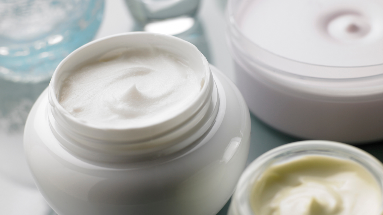Botes de crema facial abiertos sobre mesa