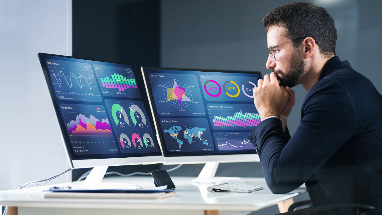 Persona analizando datos en dos monitores.