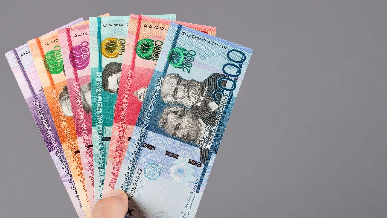 Mano sosteniendo billetes de peso dominicano.