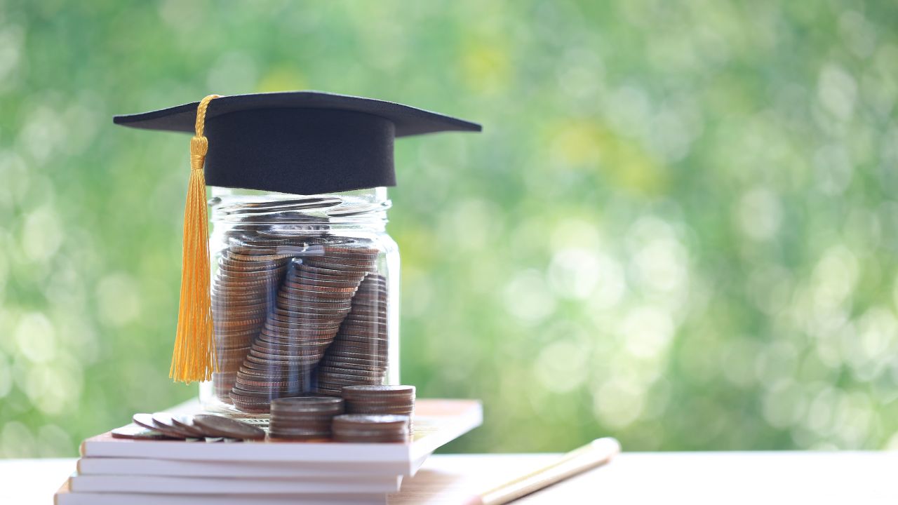 Tarro de monedas con birrete académico.