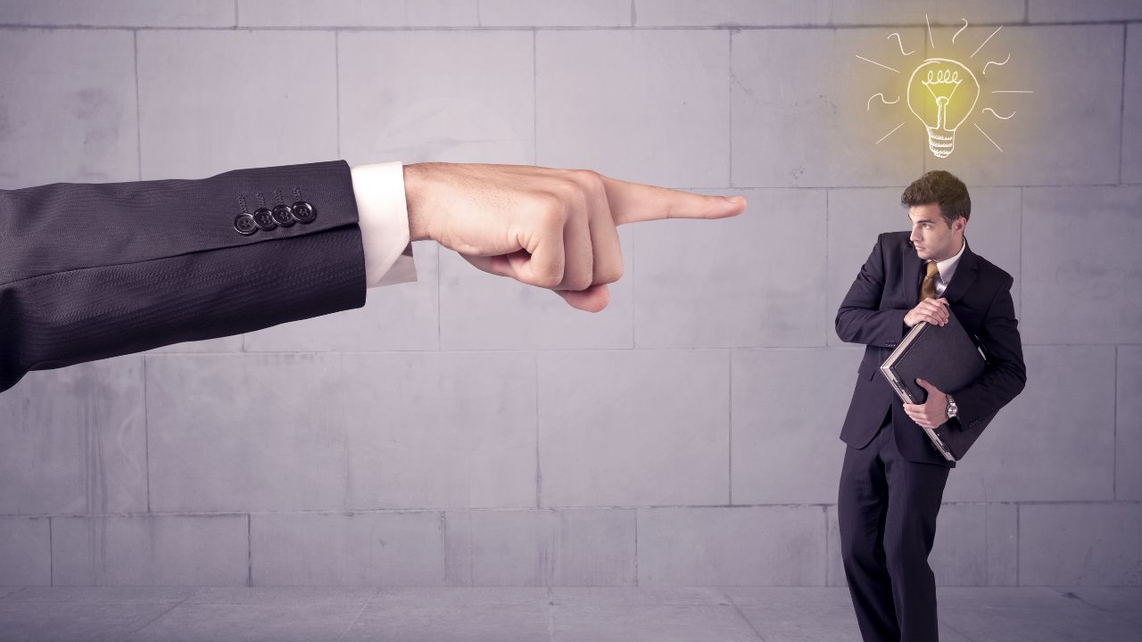 Gran mano señala a hombre asustado con carpeta