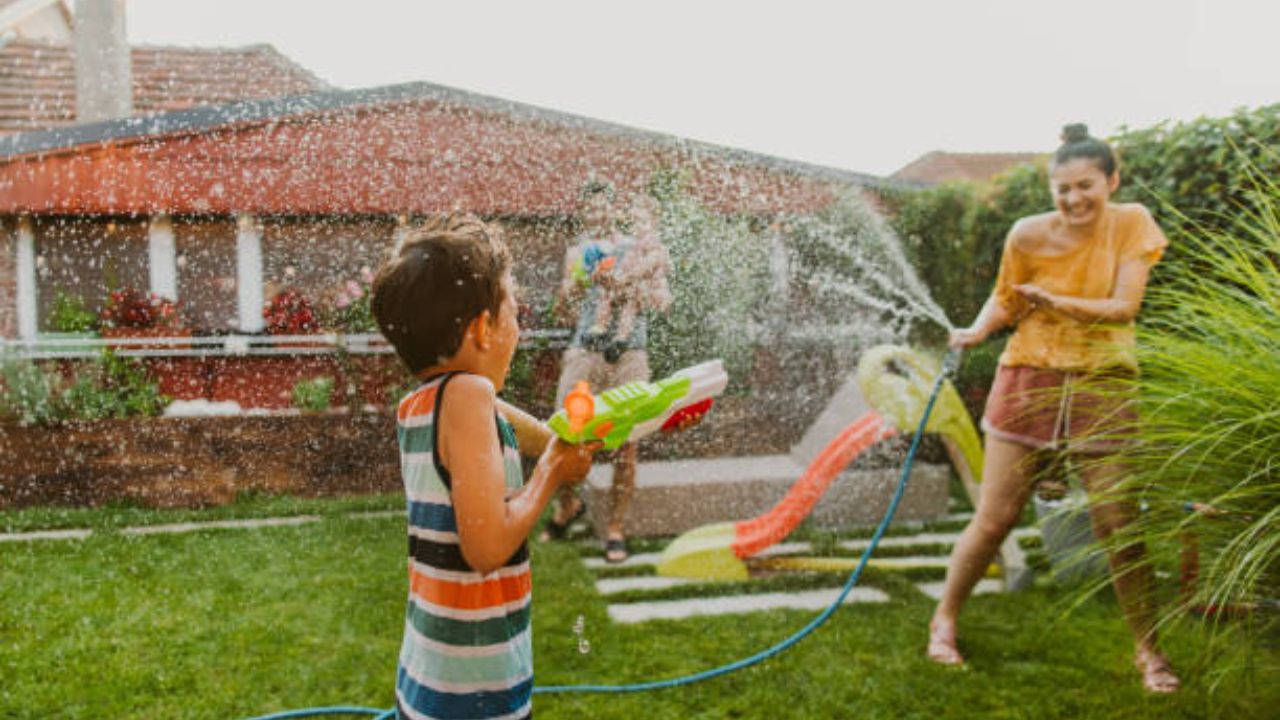 Niños jugando con agua en jardín