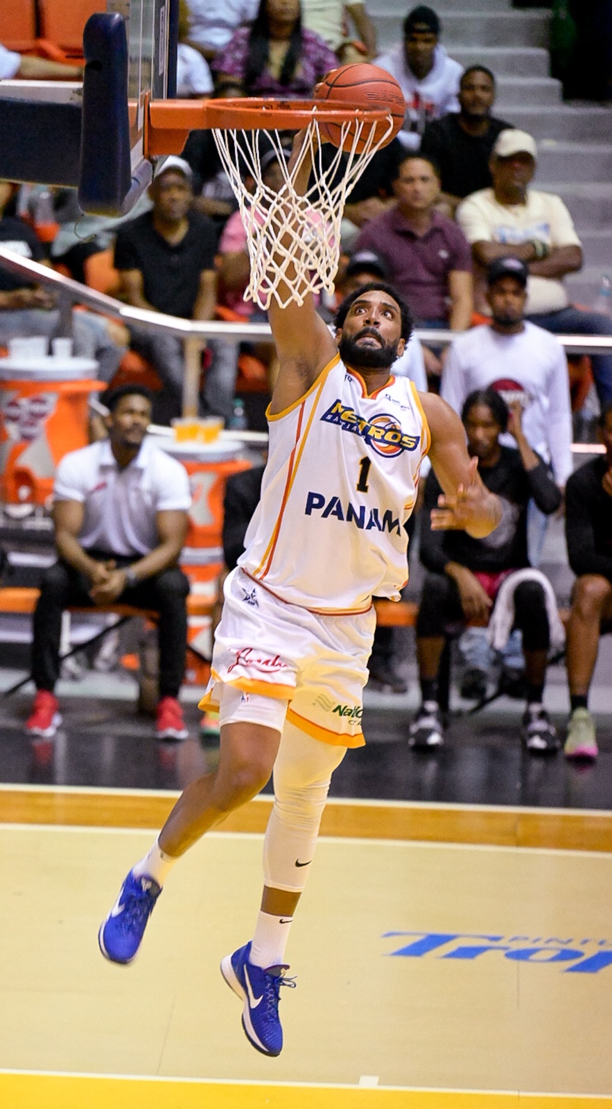 Jugador encestando en partido de baloncesto.