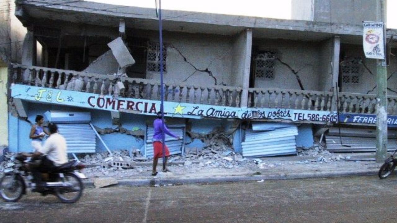 Edificio dañado por terremoto en calle concurrida.