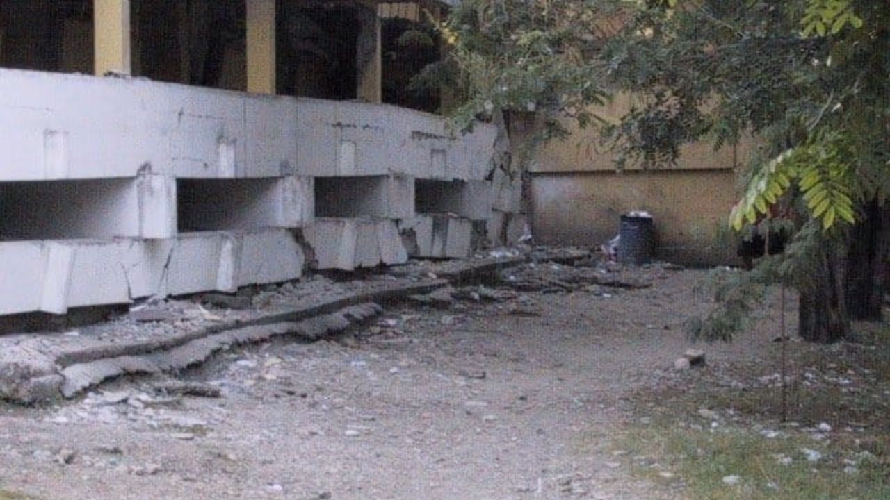 Estructura de edificio dañada junto a árboles y escombros.