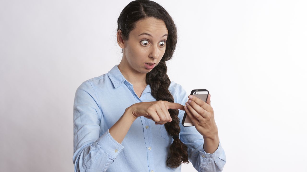 Mujer sorprendida mirando el teléfono móvil.