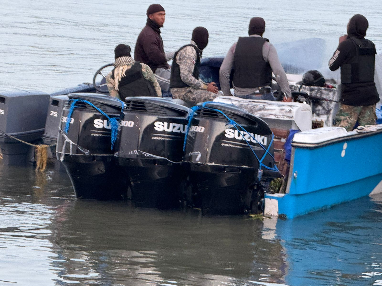Hombres en lancha con motores Suzuki en el agua.