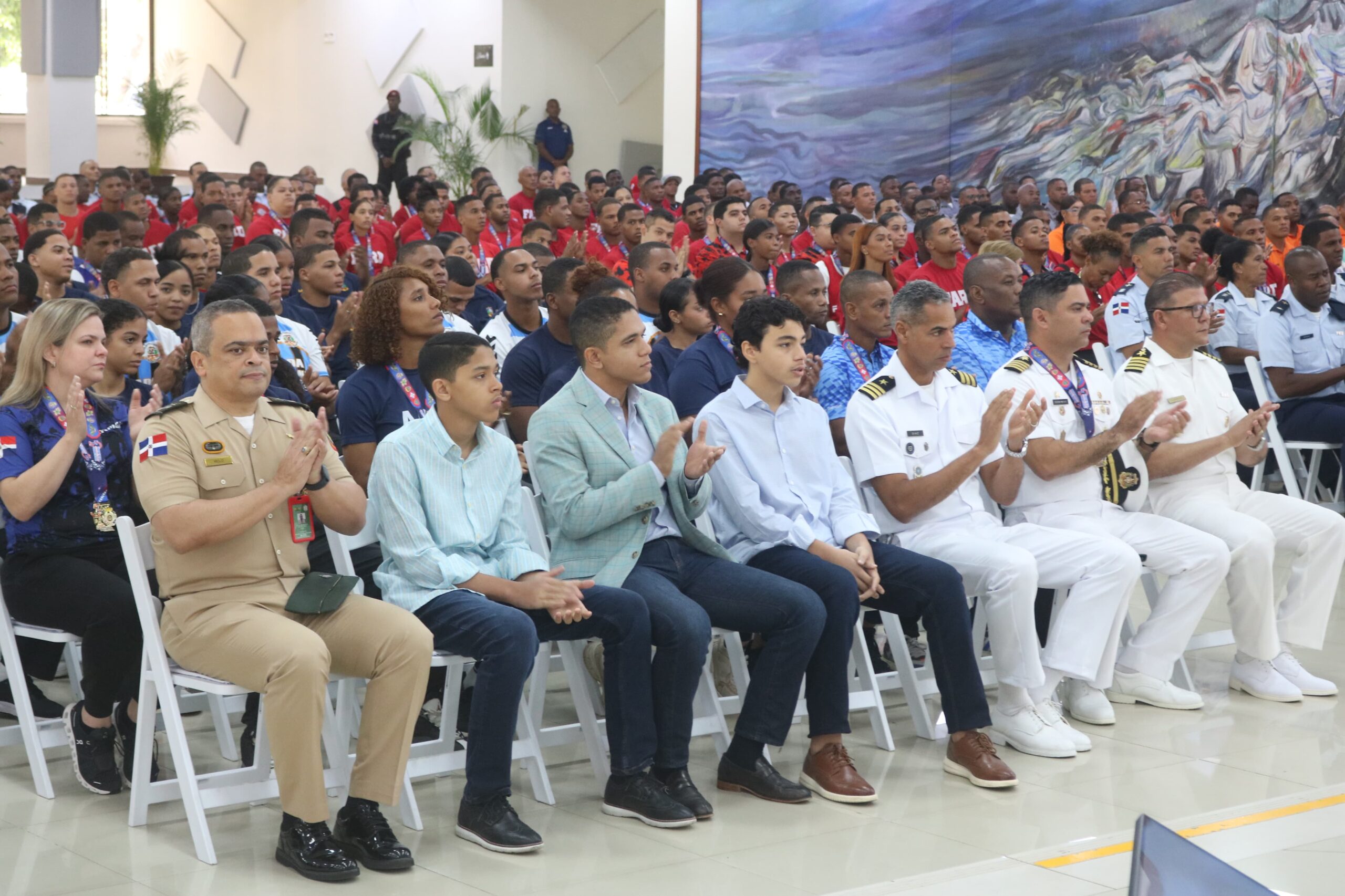 Personas sentadas aplaudiendo en evento formal.