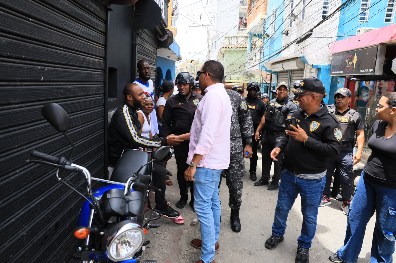 Oficiales saludan a personas en una calle concurrida.