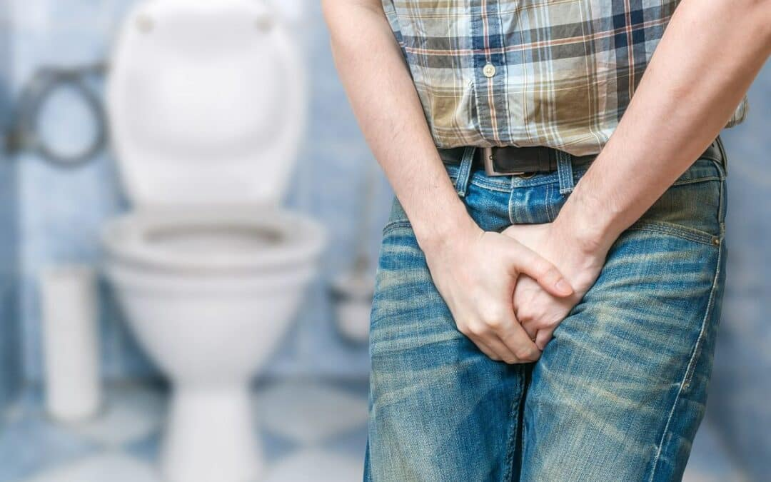 Hombre con urgencia urinaria frente a un inodoro.