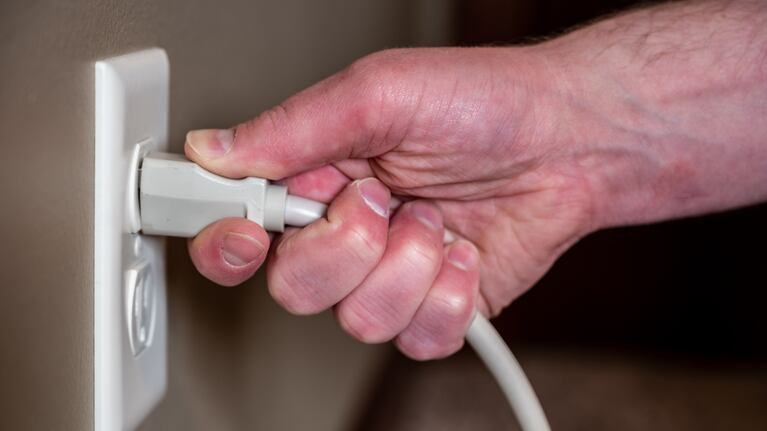 Mano desenchufando un cable de la pared