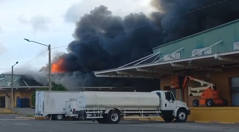 Incendio en edificio industrial con camión estacionado.