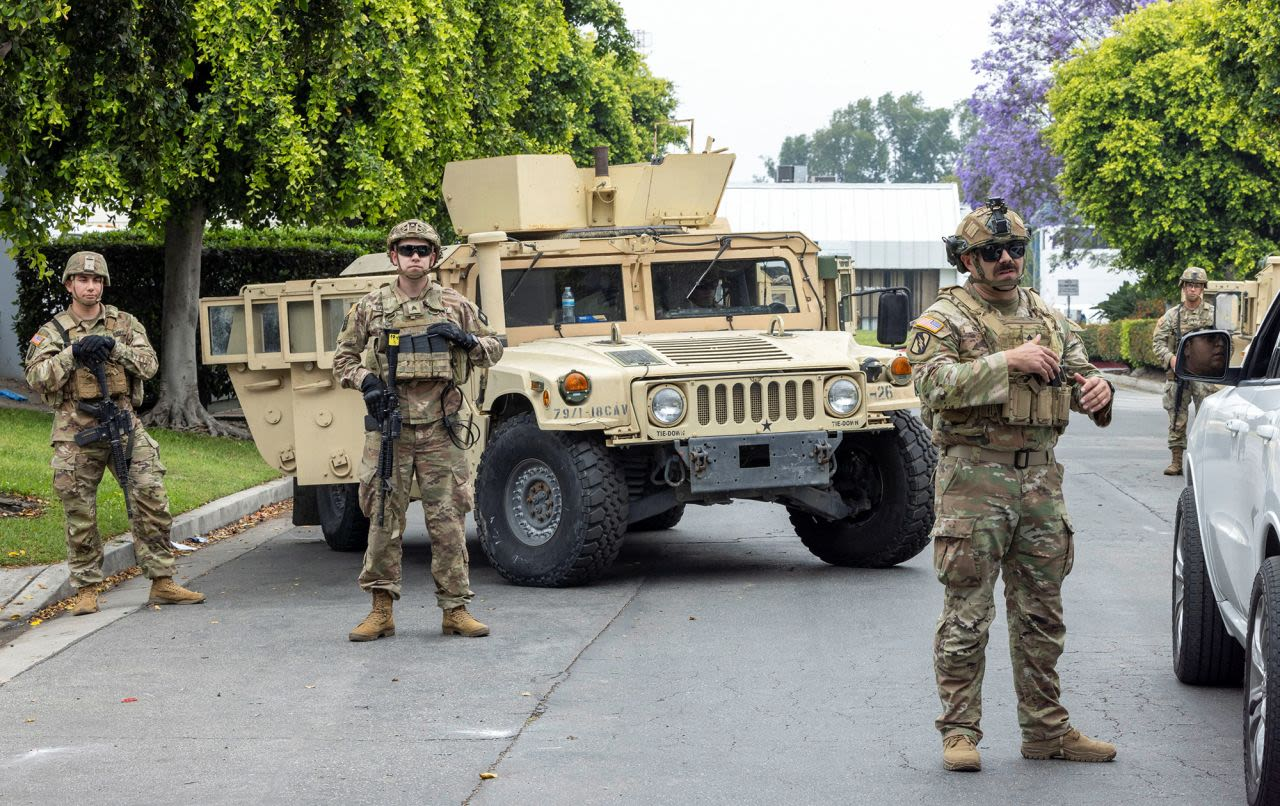 Militares frente a vehículo blindado en una calle.