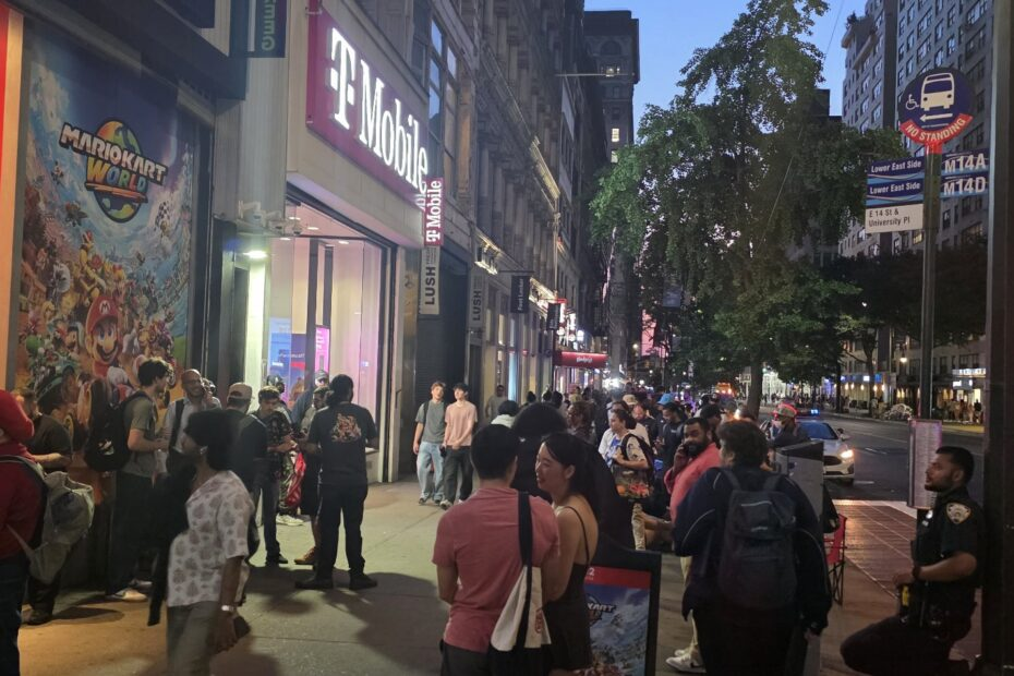 Gente hace fila frente a tienda T-Mobile de noche.