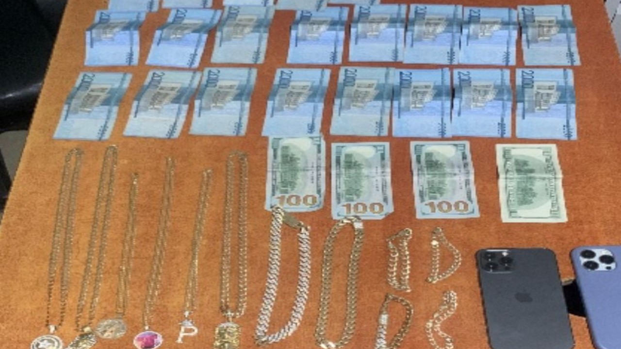 Dinero, joyas y teléfonos móviles sobre mesa marrón