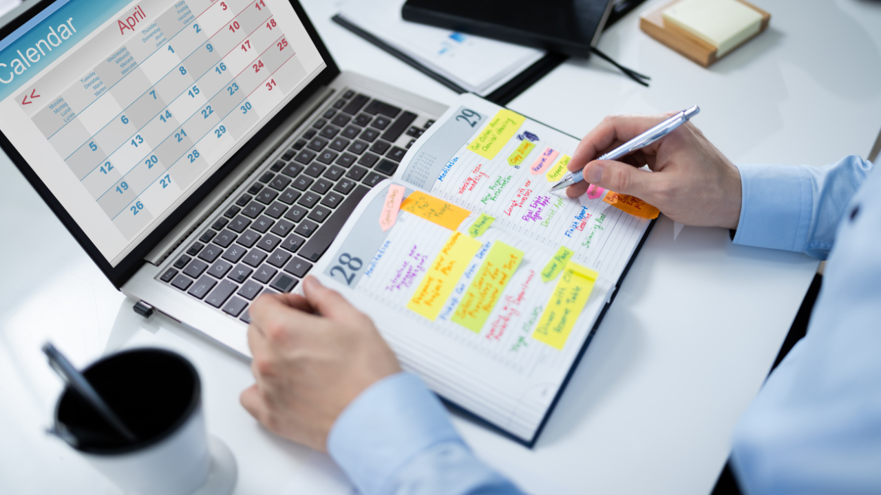 Persona organizando agenda y calendario en laptop.