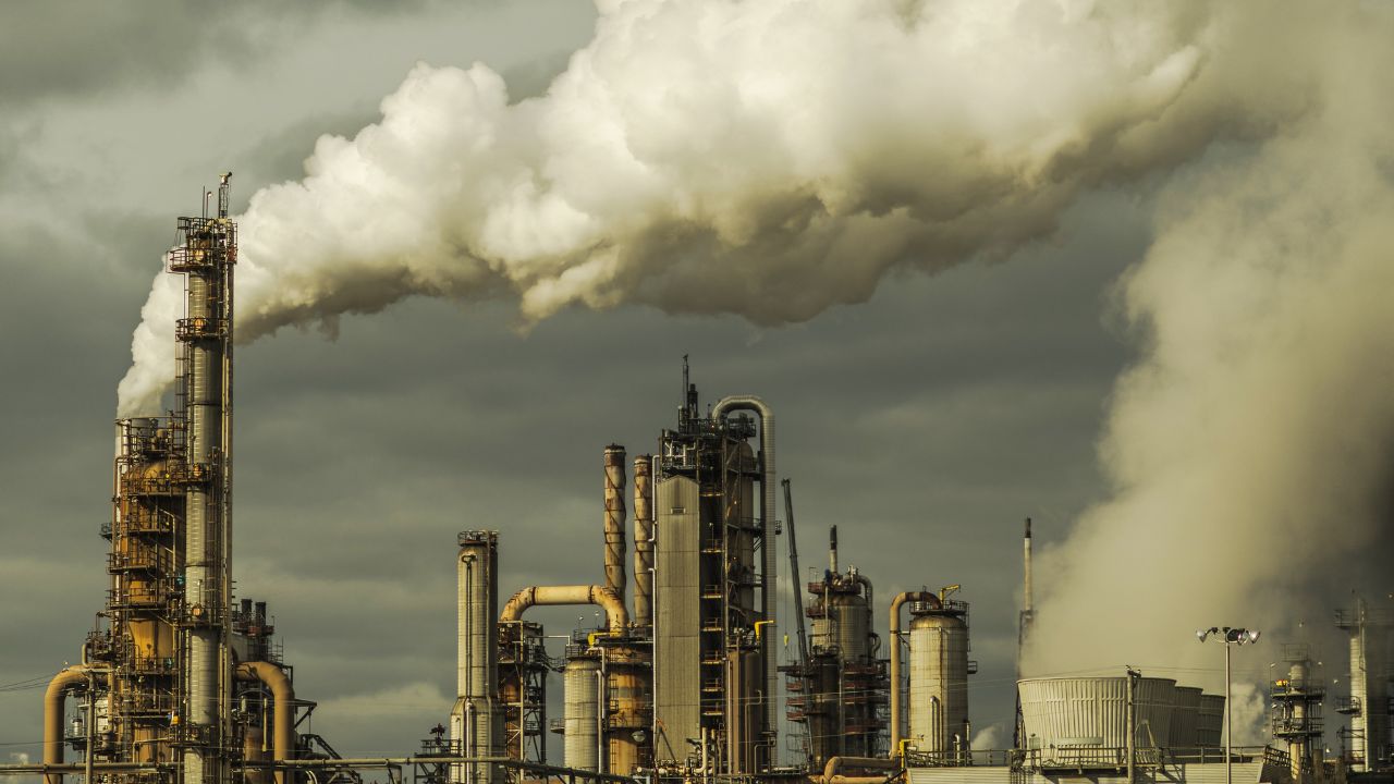 Planta industrial emitiendo humo hacia el cielo nublado.