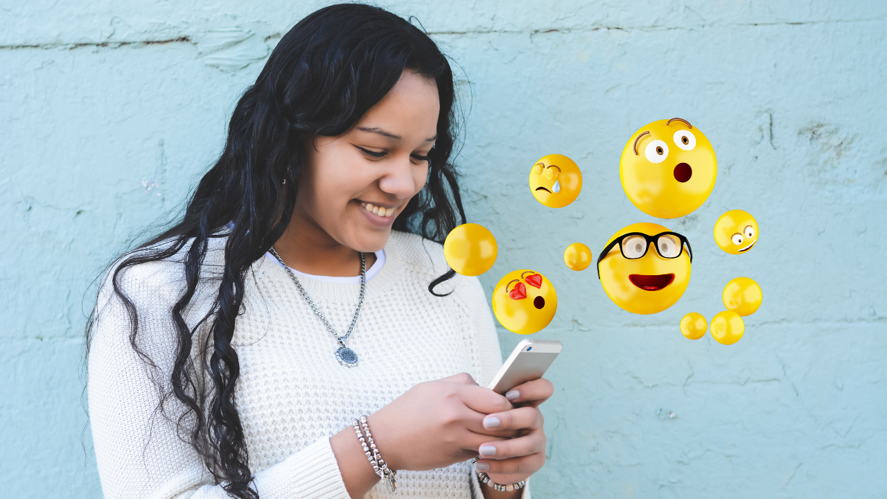 Mujer sonriente usando móvil, emojis flotando alrededor.