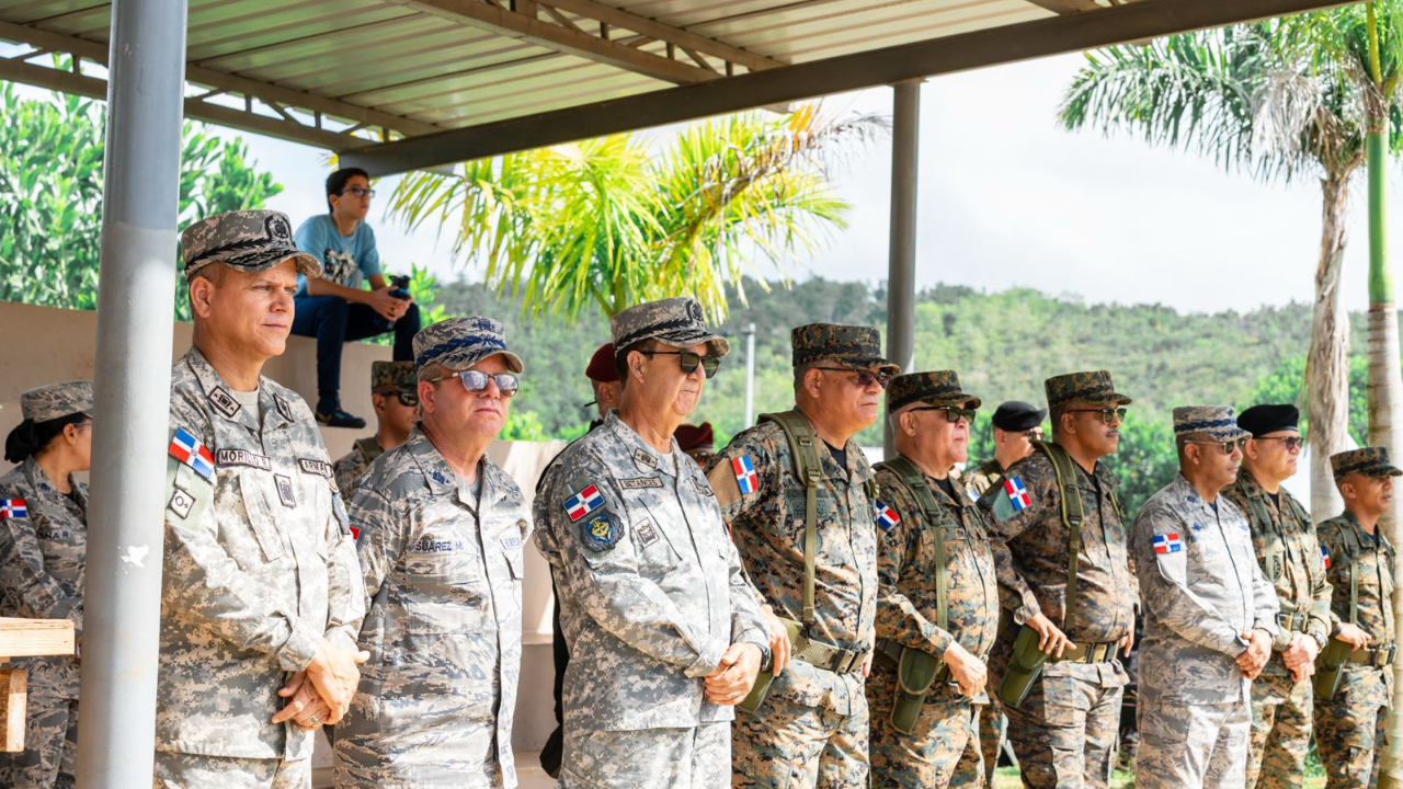 Militares en formación bajo techo, uniforme mimetizado.