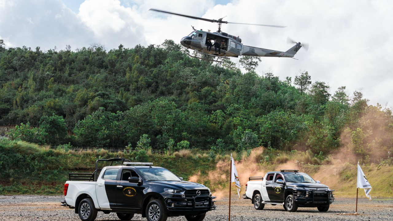 Helicóptero y camionetas en una zona boscosa.