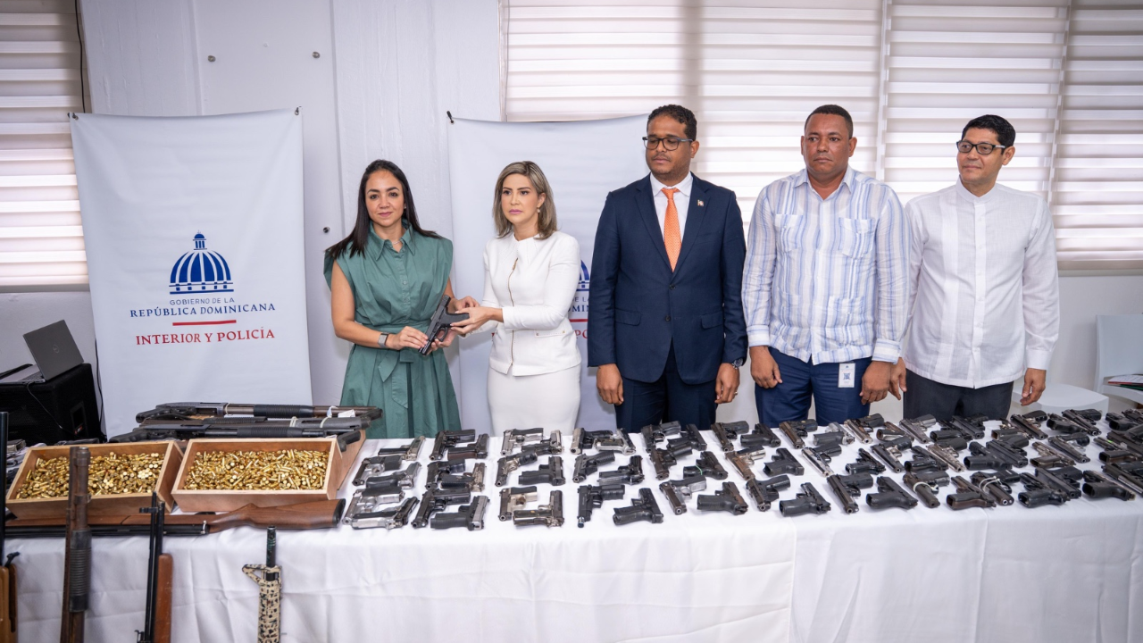 Funcionarios frente a mesa con armas incautadas.