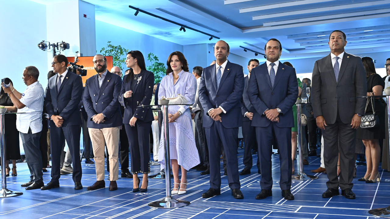 Personas formales en evento con decorado azul y blanco.