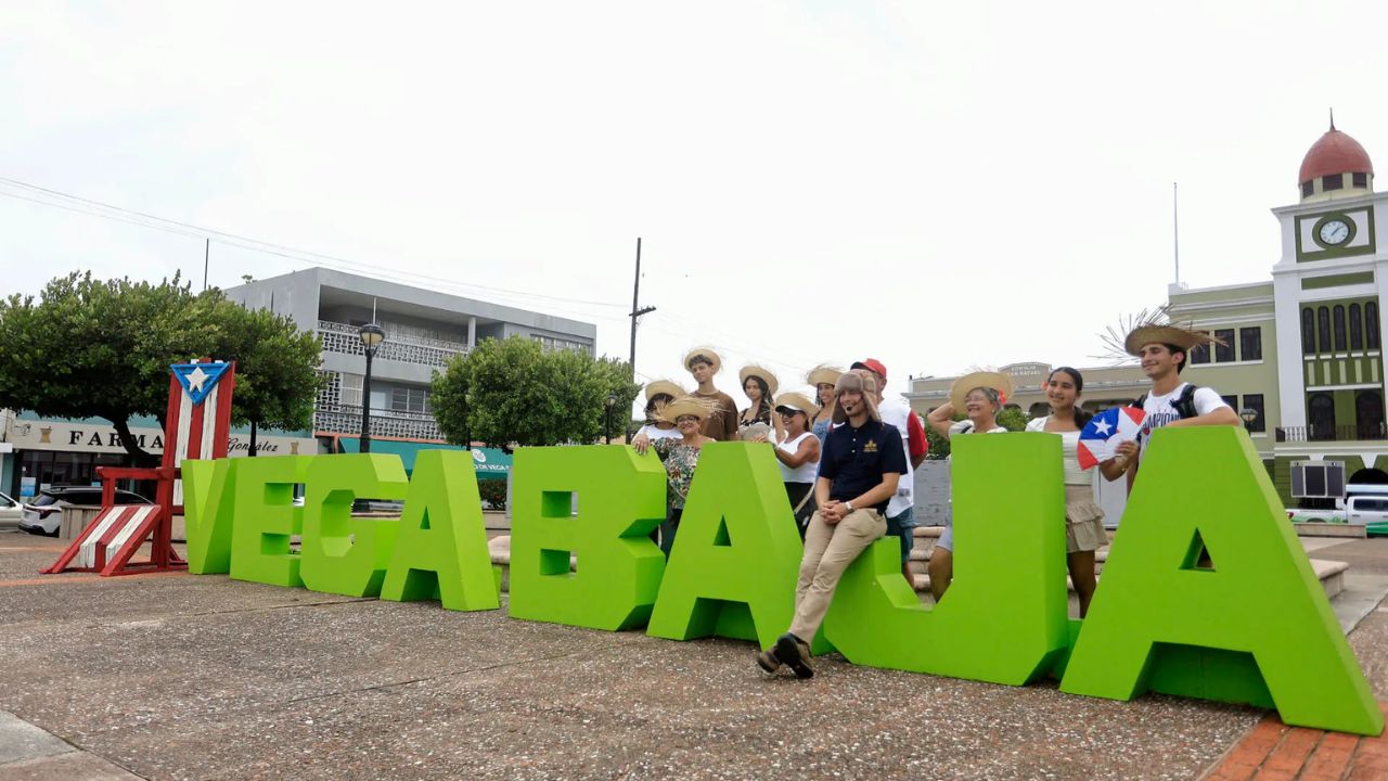 Personas junto al letrero verde Vega Baja, Puerto Rico.
