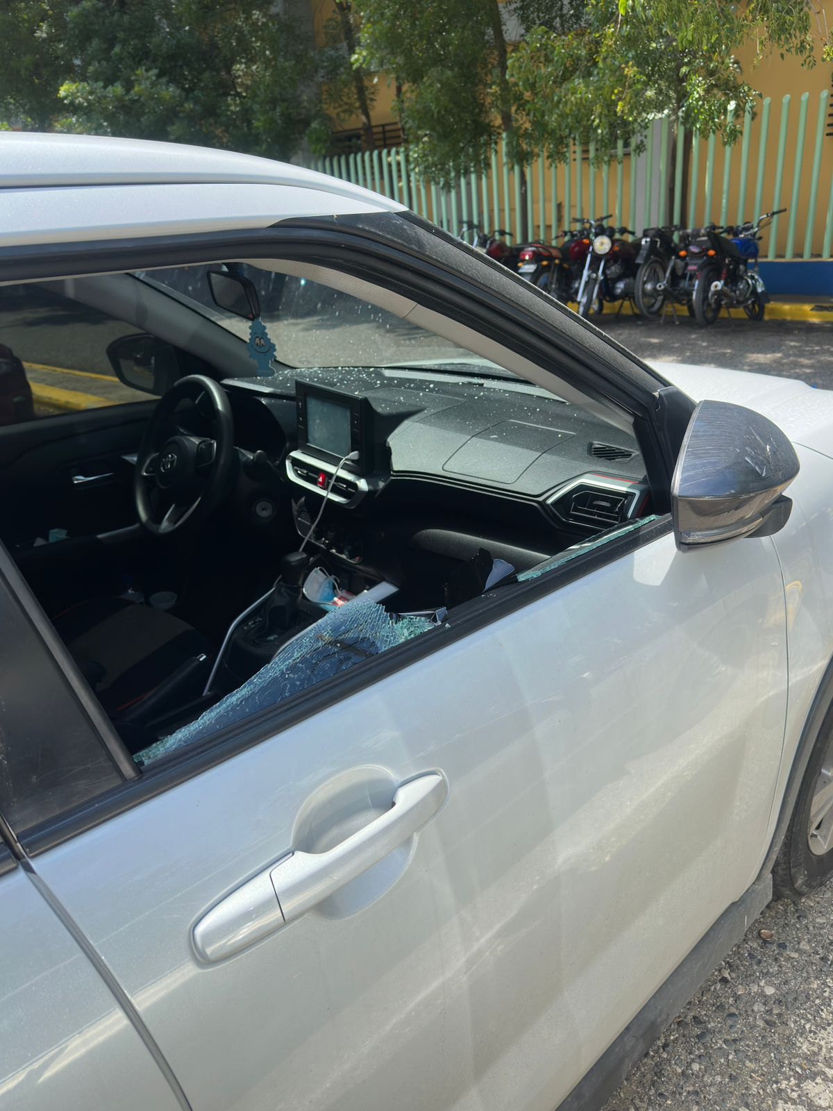 Ventana rota de coche estacionado, interior visible.