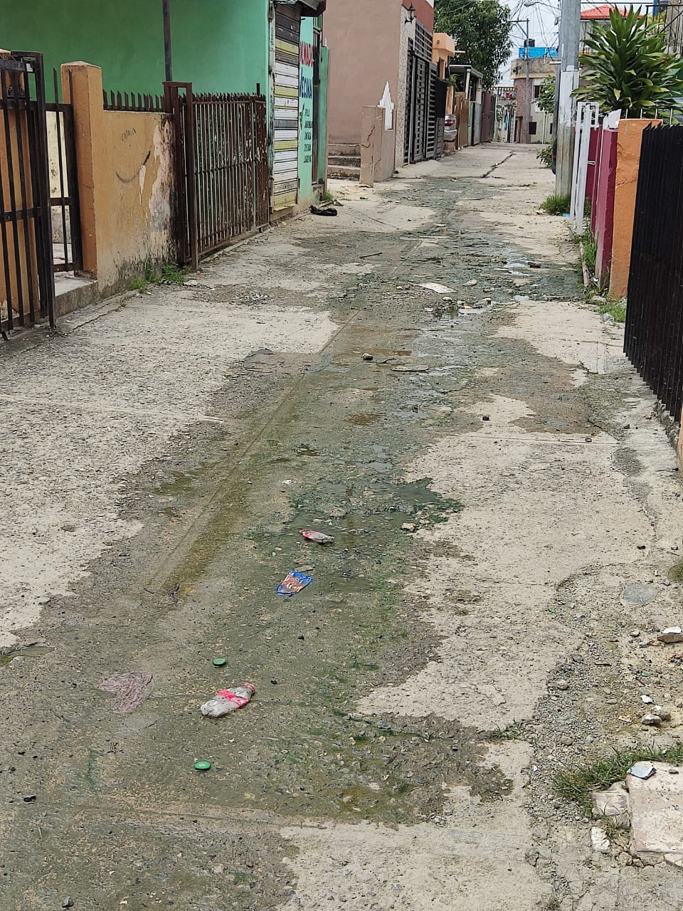 Callejón con charcos y basura al aire libre.