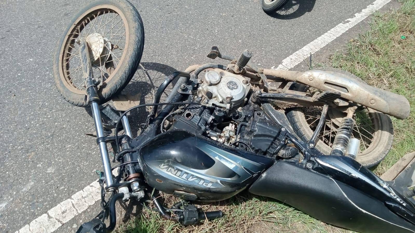 Motocicleta accidentada en el asfalto al lado del césped.