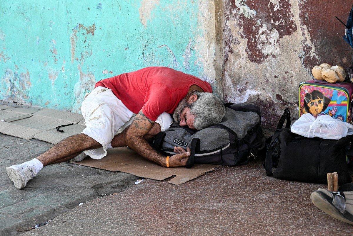 Hombre durmiendo en la calle con bolsas.