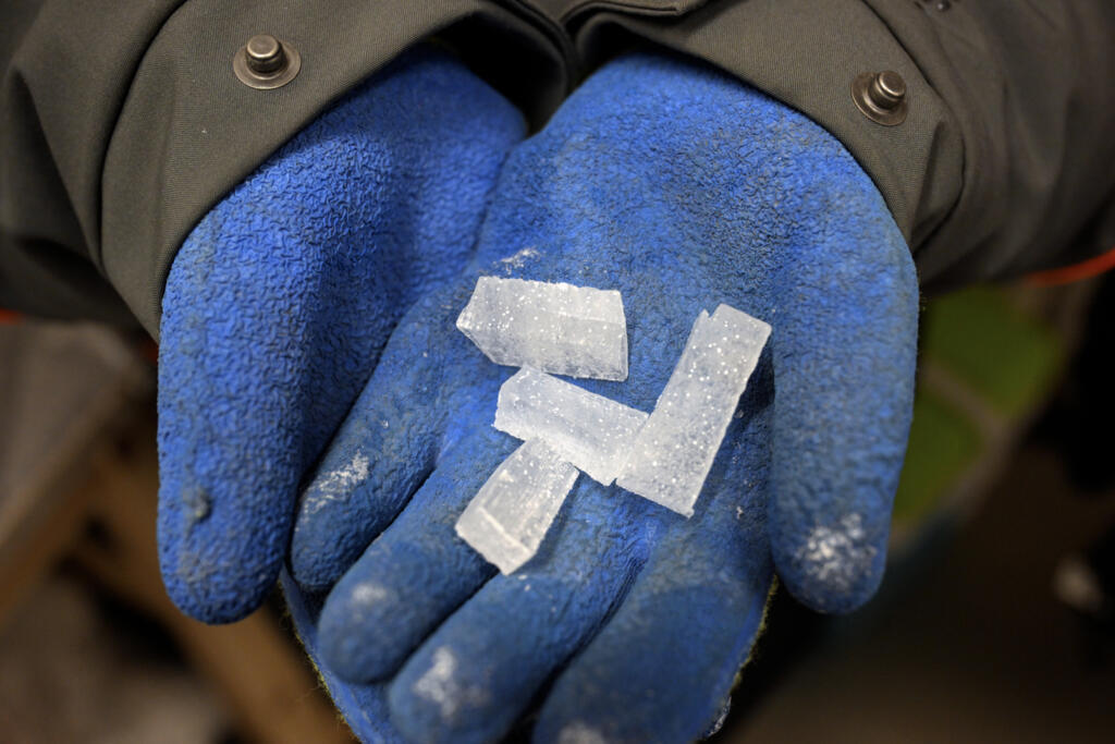 Manos con guantes sosteniendo cristales de hielo