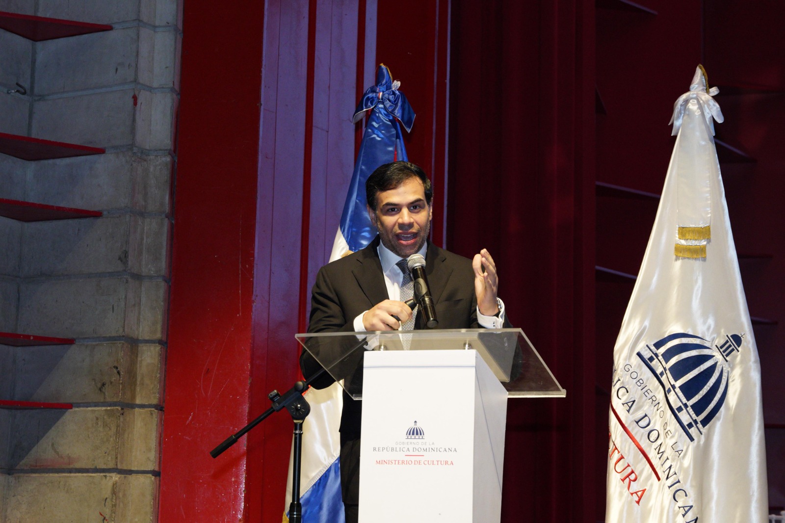 Hombre hablando en un podio con banderas.