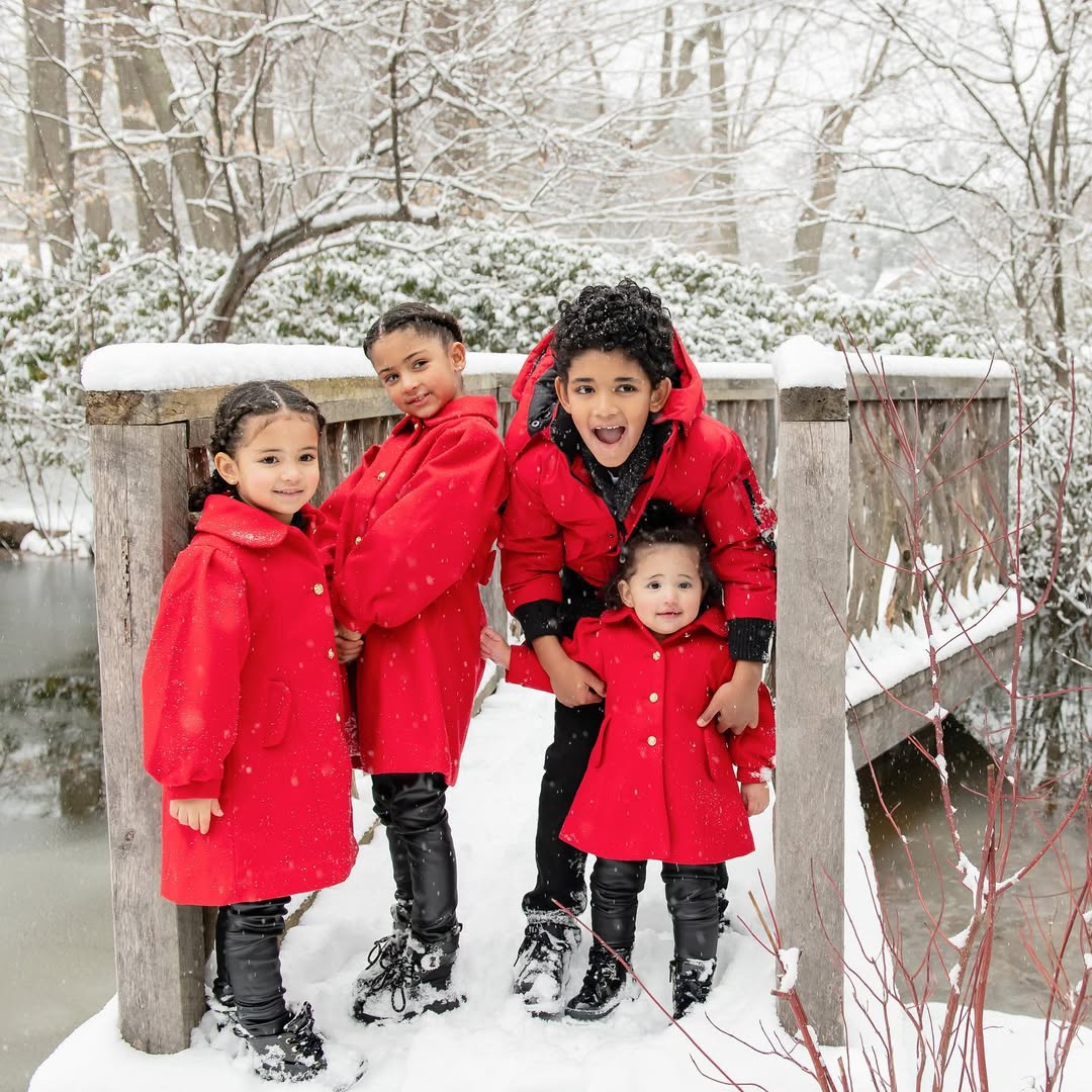 Cuatro niños con abrigos rojos en la nieve.